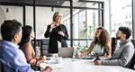 A businesswoman makes a presentation to a small group of colleagues in a conference room.