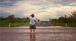 An image of a person standing knee-deep in a flooded road. 