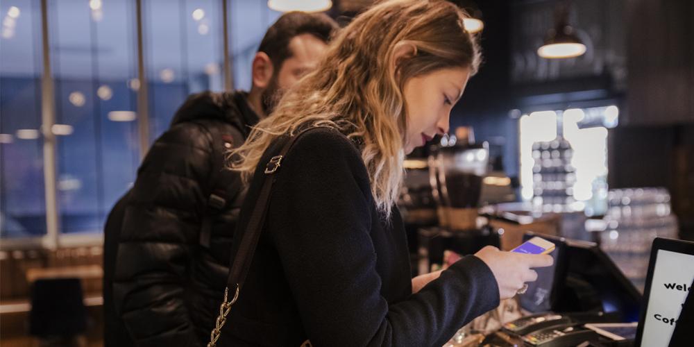 Woman using a mobile app to pay in a coffee shop