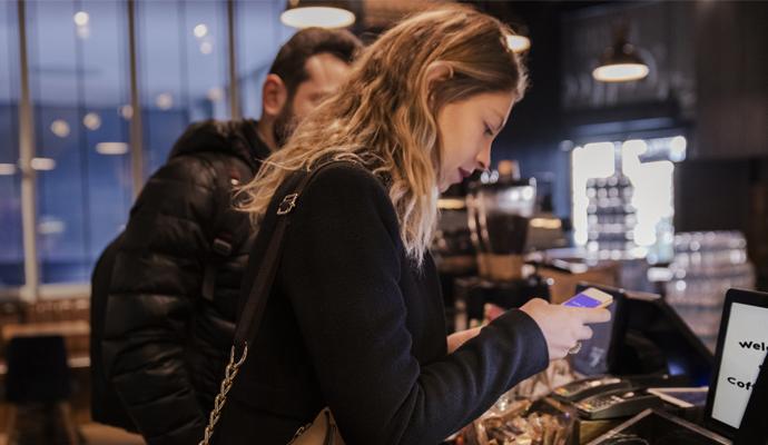 Woman using a mobile app to pay in a coffee shop 