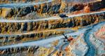 A high-angle view shows a truck ascending out of a copper quarry.