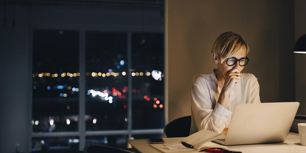 Woman in deep concentration at her desk at night Woman in deep concentration at her desk at night