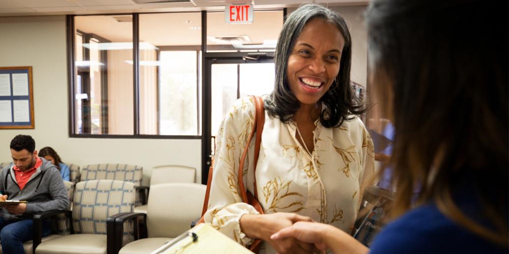 A photograph of a smiling patient being admitted to a doctor’s office A photograph of a smiling patient being admitted to a doctor’s office