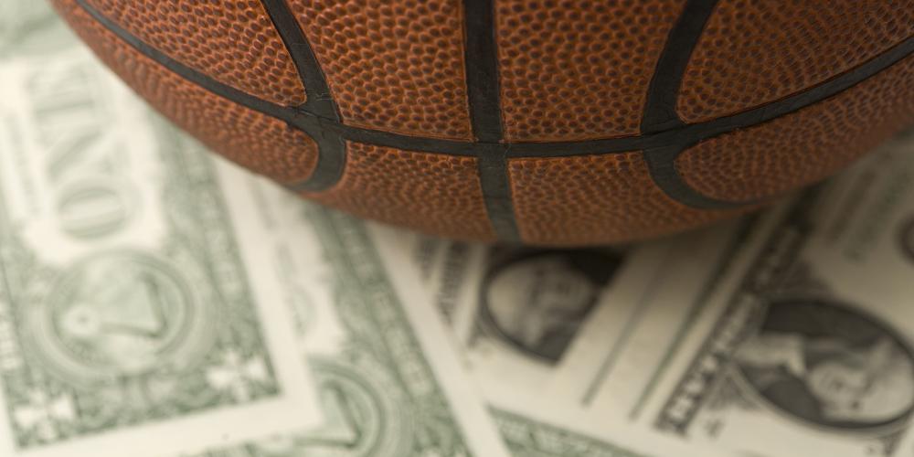 A close-up photo of a basketball sitting on dollar bills A close-up photo of a basketball sitting on dollar bills