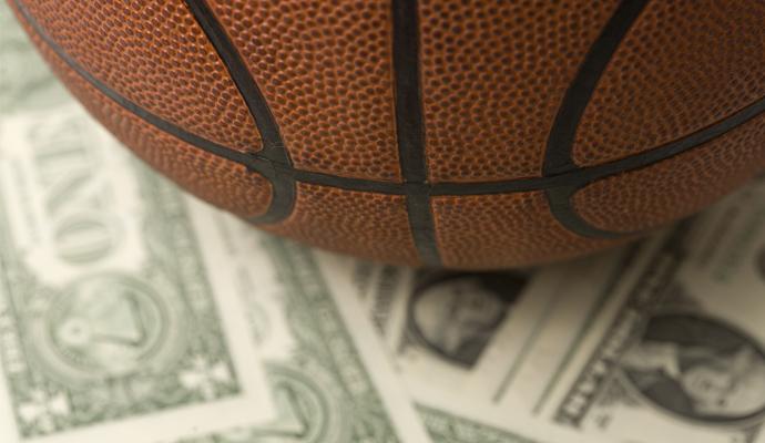 A close-up photo of a basketball sitting on dollar bills