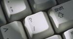 A close-up view of a computer keyboard focuses on the question-mark key