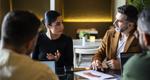 At an informal meeting, a businesswoman leads a discussion with three colleagues.