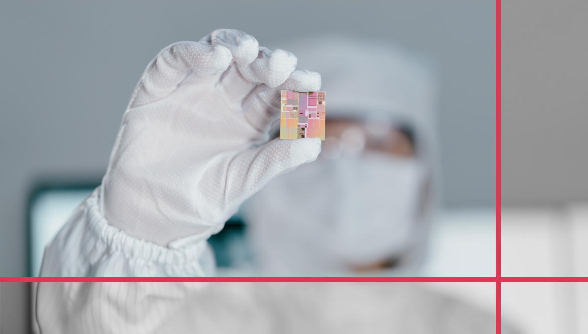 A photograph of a chip engineer in a clean-room suit holding up a chip A photograph of a chip engineer in a clean-room suit holding up a chip