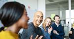 A diverse group of young, smiling workers in a conference room
