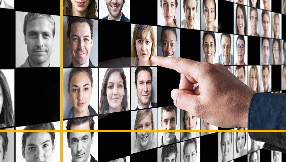 A hand pointing at a large screen displaying the faces of dozens of people A hand pointing at a large screen displaying the faces of dozens of people