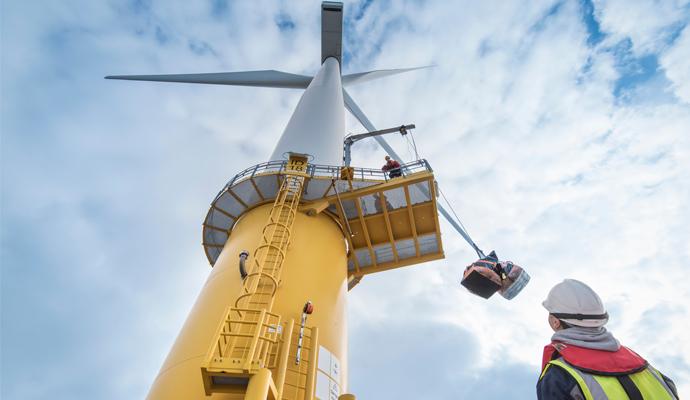 Engineers winch tools up wind turbine from boat at offshore windfarm