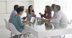 Business meeting with 6 diverse people sitting around a table discussing a topic