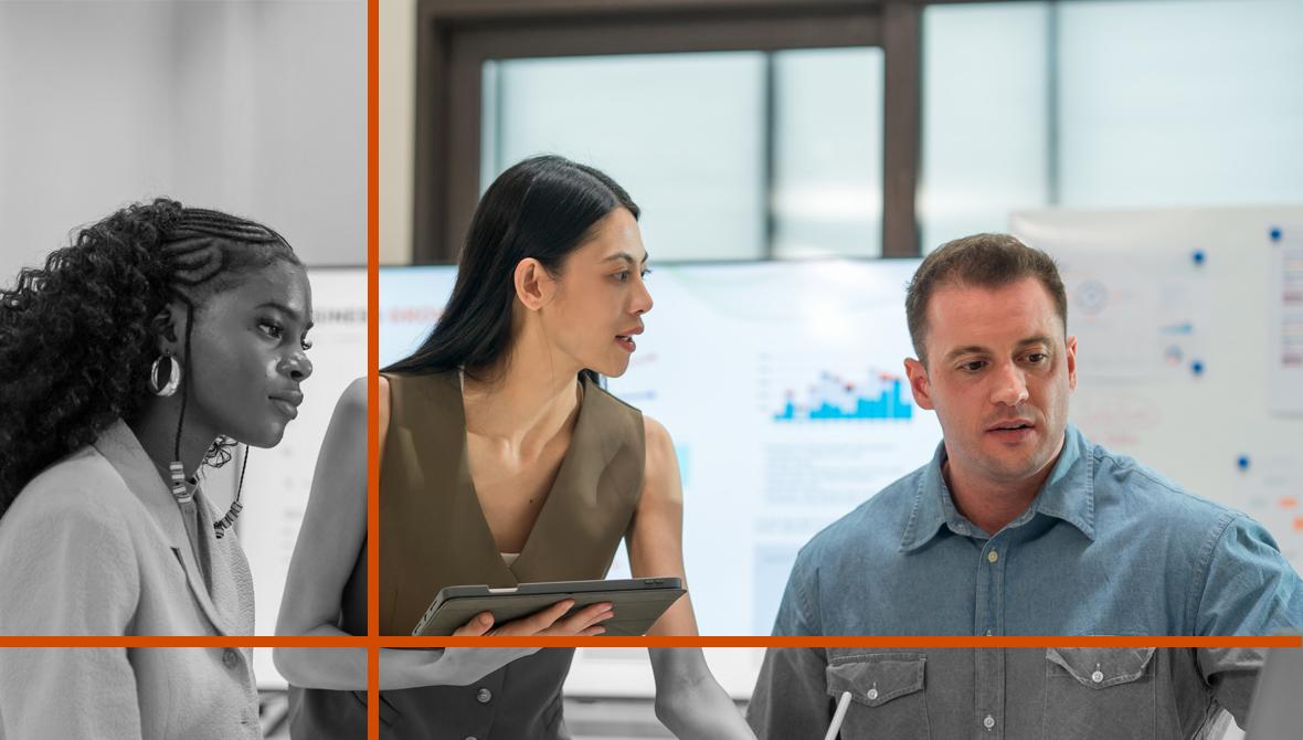 Three colleagues meet around a laptop in a casual office setting to discuss business strategy.
