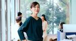 A portrait of a businesswoman with her hands on her hips and her team in the background