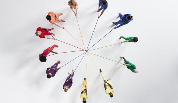 Circle of people pulling on connected ropes