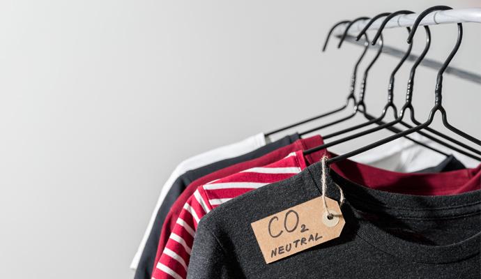 A dark gray sweater hanging on a rack, with a tag that reads "CO2 neutral"