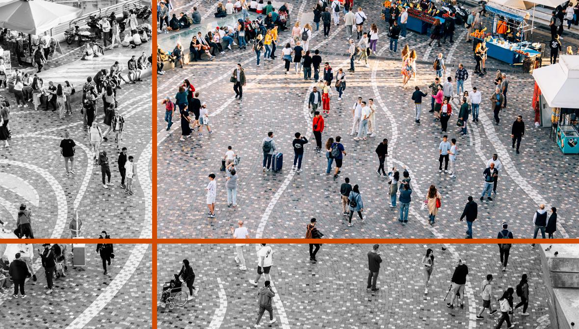 An overhead view of a public square, patterned with stone tiles, shows people walking, gathering, and sitting amid a fountain and market stalls.