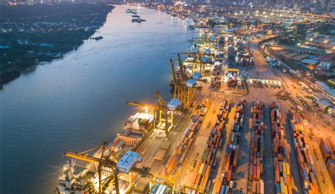 An image of a port at sunrise shows docked cargo ships and containers