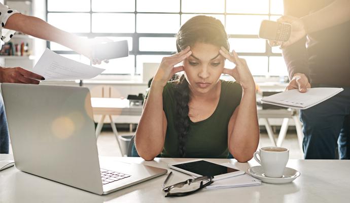 Stressed out businesswoman surrounded by colleagues needing help