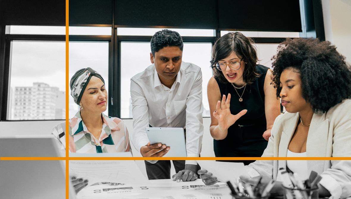 A group of four coworkers grow frustrated as they meet and talk around an office table.