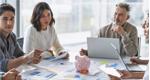 Group of business people in a meeting reviewing financial documents with a piggy bank sitting on top