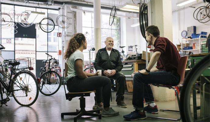 A small team of bicycle mechanics having a meeting together in their bike workshop.
