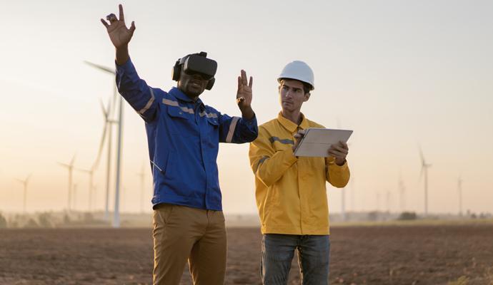 Engineer standing in a field at a wind farm wearing VR glasses