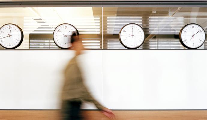 Businessman walking by wall clocks showing different time zones