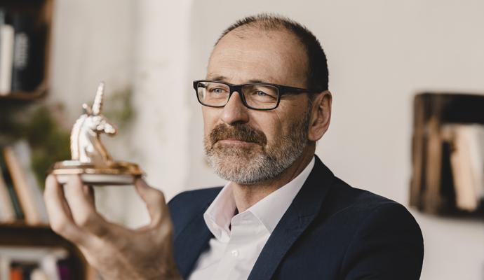 Mature businessman holding a unicorn figurine