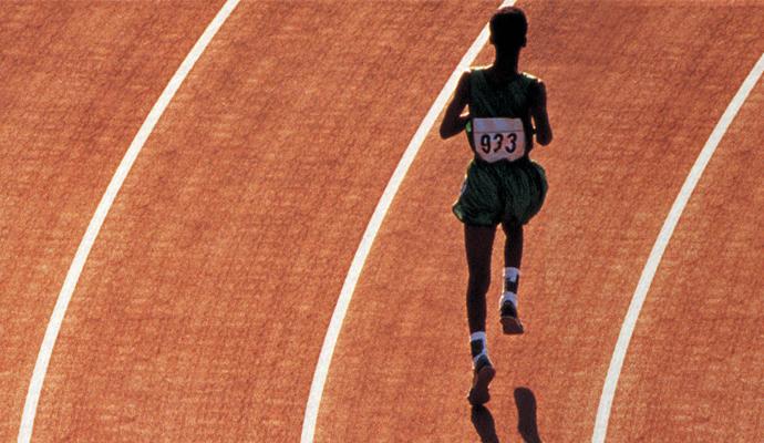 A solitary runner rounds the corner of a track