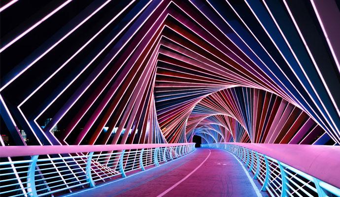 Photograph of the roadway of a bridge with lighted overhead beams Photograph of the roadway of a bridge with lighted overhead beams