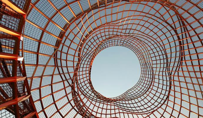 An irregular cylinder of orange mesh, open to a a clear blue sky