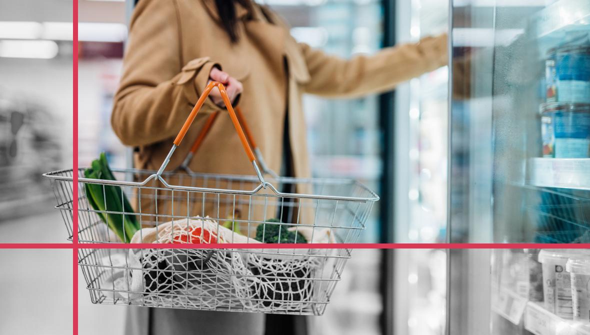 Cropped photo of a woman carrying a shopping basket and reaching into a refrigerated case in a supermarket Cropped photo of a woman carrying a shopping basket and reaching into a refrigerated case in a supermarket