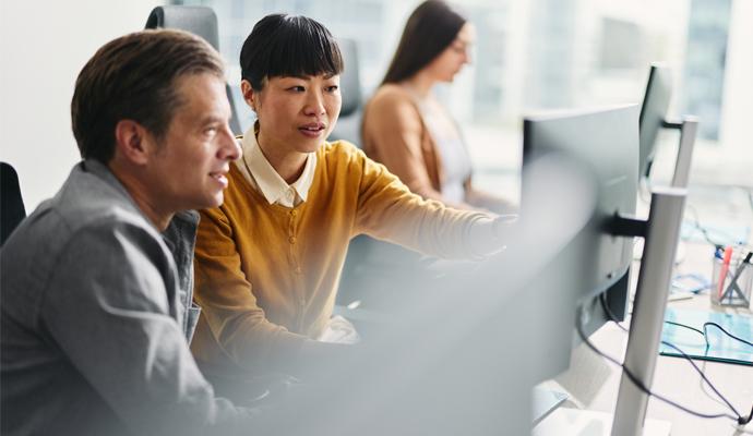Two business colleagues working intently together on the same computer station in a corporate office