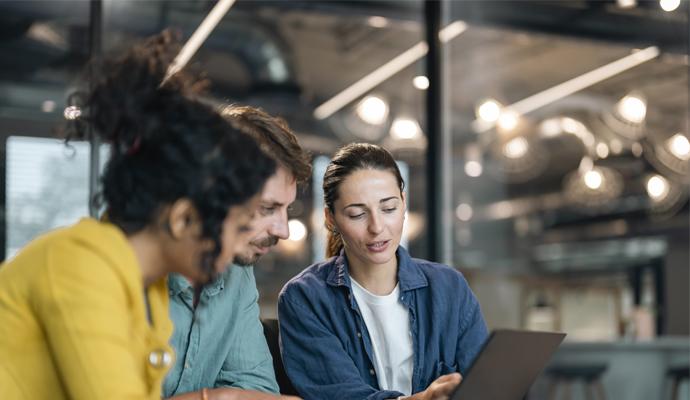 Two women and a man at work, reviewing a laptop screen