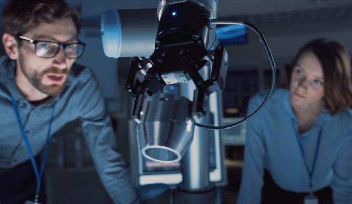Engineers study a robotic device during a technology demonstration