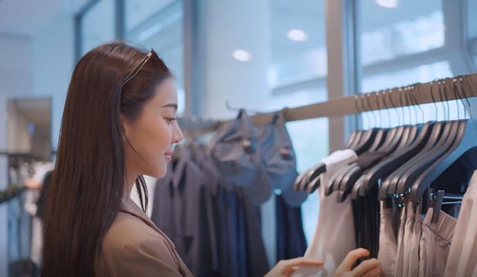 A woman browsing clothing on a rack inside a modern retail store