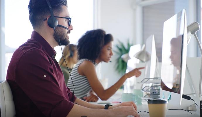 Customer support staff working at computers in a bright, modern office