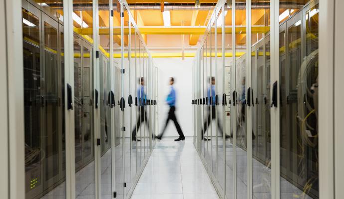 IT professional moving through a secure data center lined with server cabinets.