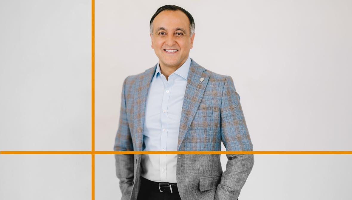 Zahid Salman, wearing a light blue dress shirt and a blue-gray plaid blazer, smiling against a plain background.