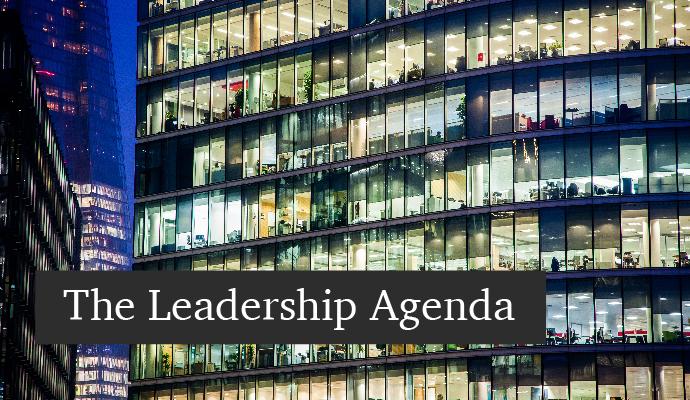 A photograph of a building with offices lit up at night with the words "The Leadership Agenda" superimposed