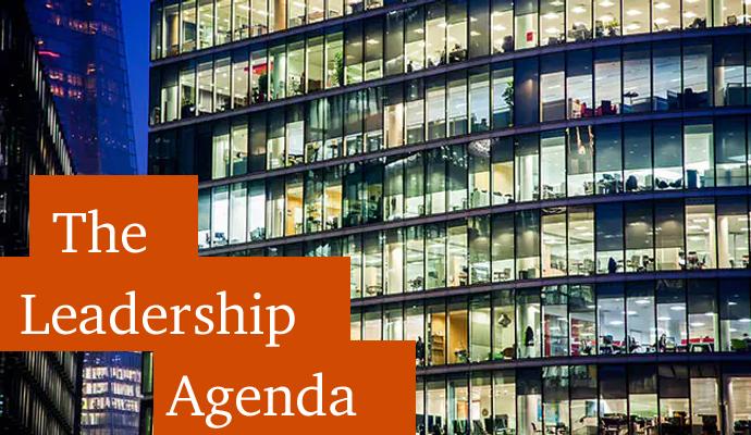 A photograph of a building with offices lit up at night with the words "The Leadership Agenda" superimposed