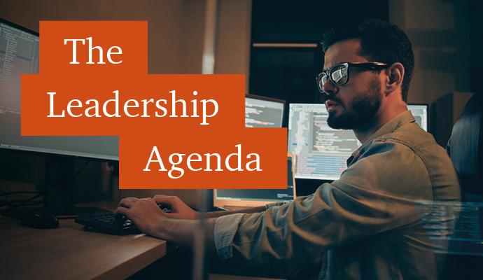 Photograph of a tech worker in front of a bank of computer monitors  with the words "The Leadership Agenda" superimposed