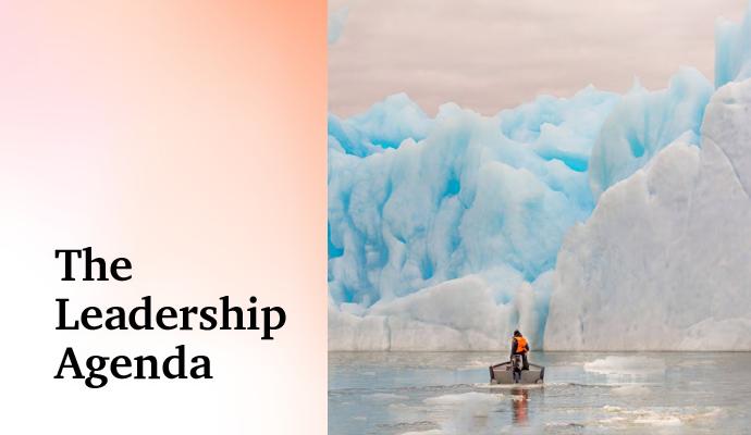 Person in small boat in front of large iceberg