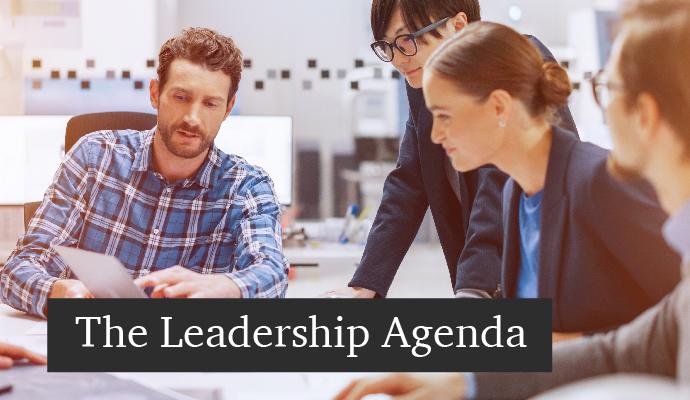 A photograph of coworkers gathered around a table with the words "The Leadership Agenda" superimposed