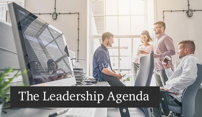 A photograph of co workers chatting in a casual office setting  with the words "The Leadership Agenda" superimposed