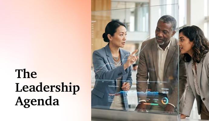 A group of colleagues discusses data displayed on a transparent screen as one person points toward the information.