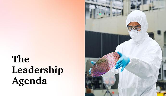 Photograph of a worker in a white protective suit holds a reflective semiconductor wafer with the words "The Leadership Agenda" superimposed