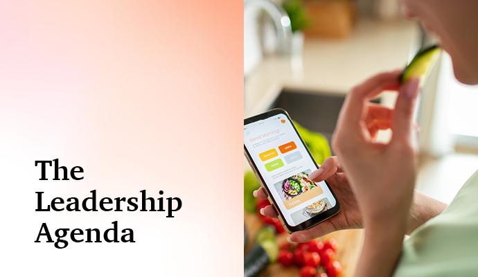 Photograph of a person's hand holding a phone while eating with the words "The Leadership Agenda" superimposed