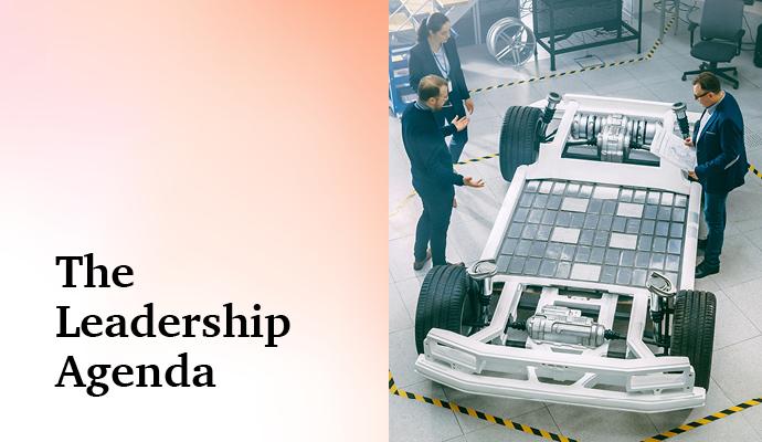 Team reviewing an electric vehicle chassis in a modern innovation lab with the words "The Leadership Agenda" superimposed